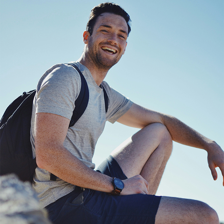 man sitting on rock smiling