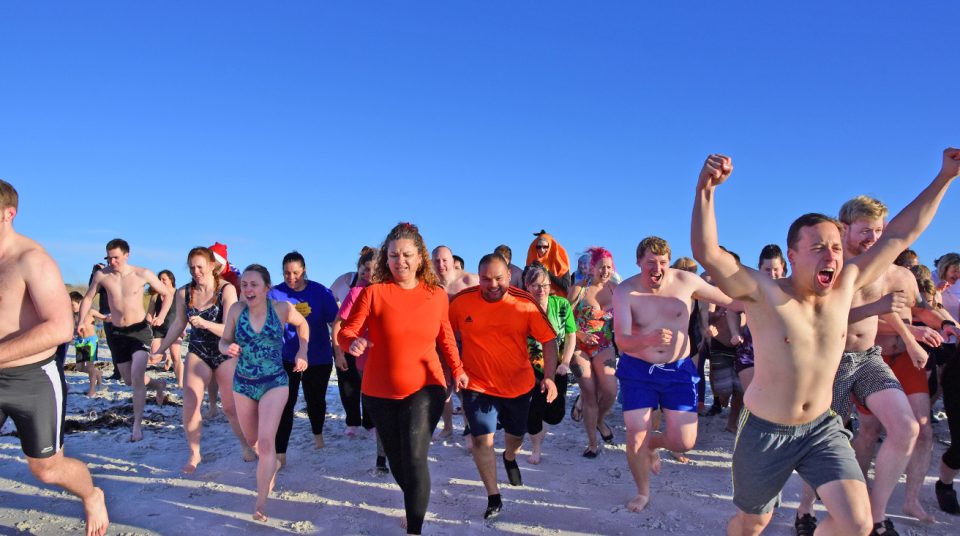 Participants race into the beach for the midwinter swim, Surf Ba